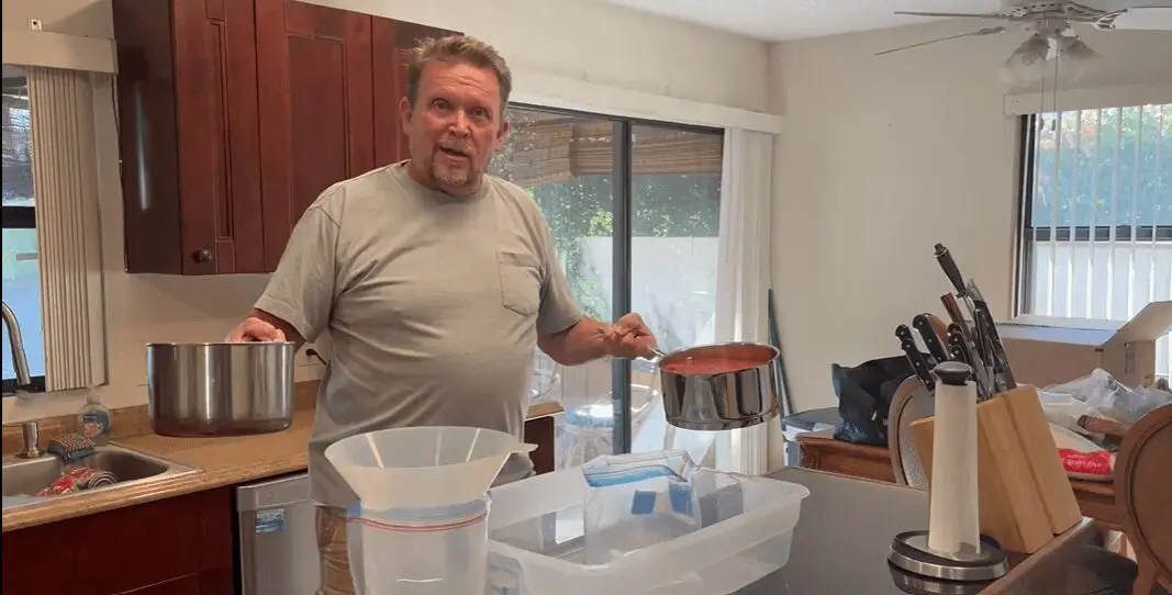 A man standing in front of a pan and some cups.